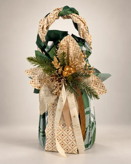 Confezione alta a borsetta per pandoro, in carte verdi e crema a motivi geometrici, con manico intrecciato, nastri Buon Natale e decorazioni oro