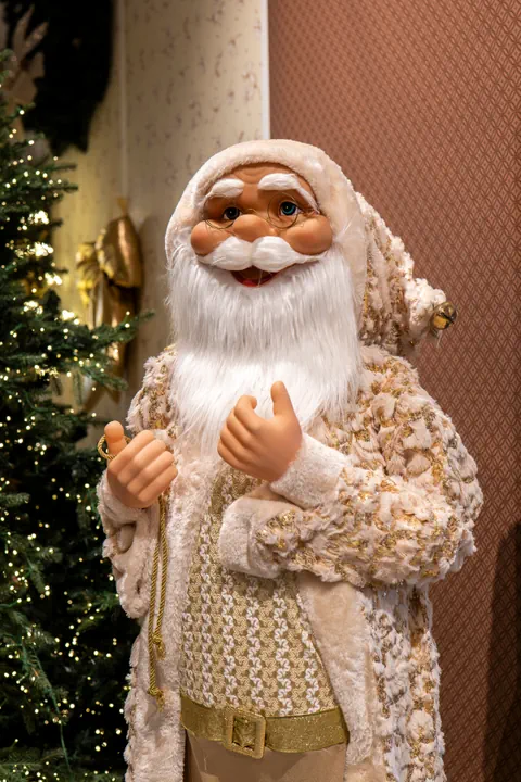 Un Babbo Natale vestito di bianco e oro, con il cappotto in pelliccia e la cintura dorata