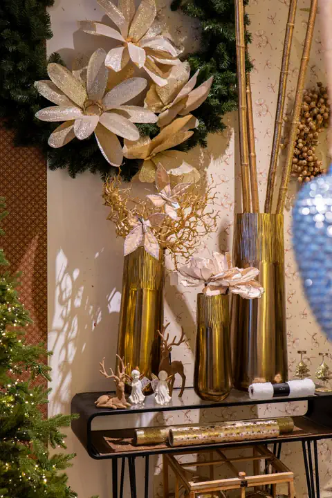 Grandi fiori color champagne su una ghirlanda e in vasi oro alti, sopra una consolle nera con piccoli angeli